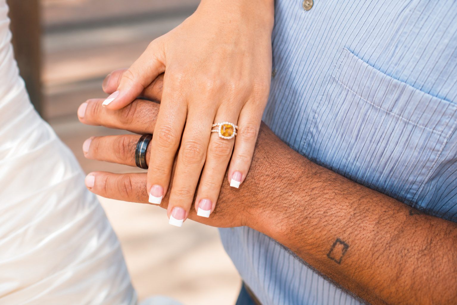 Close detail of an engaged couple's hands and rings