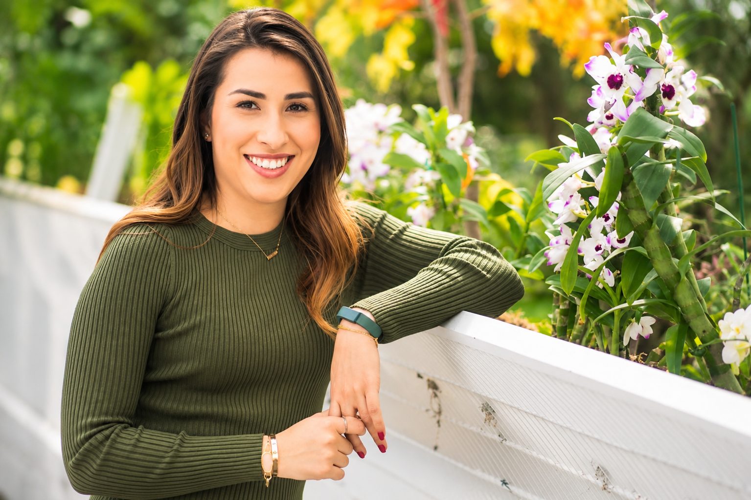 Outdoor professional headshot of a woman leaning against a white planter