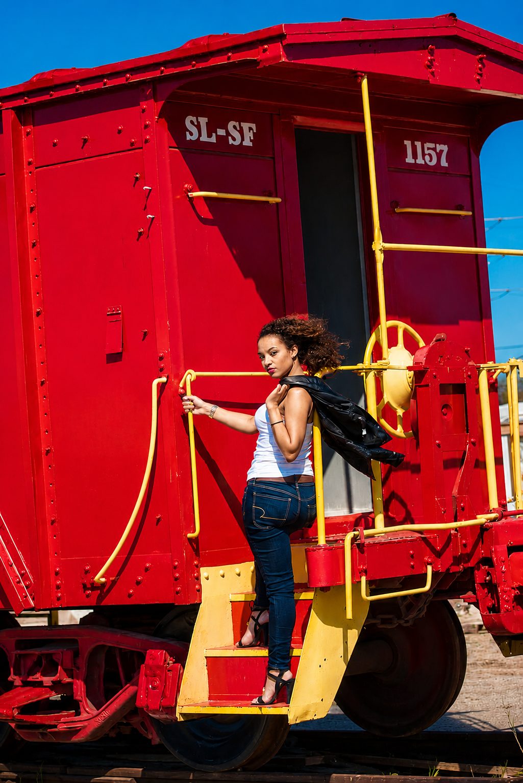 Full-length editorial portrait beside a red Frisco caboose