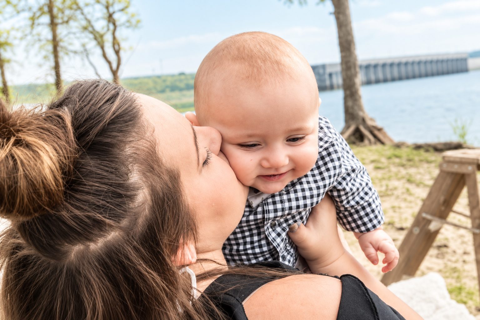 Mother kissing her baby son beside a lake