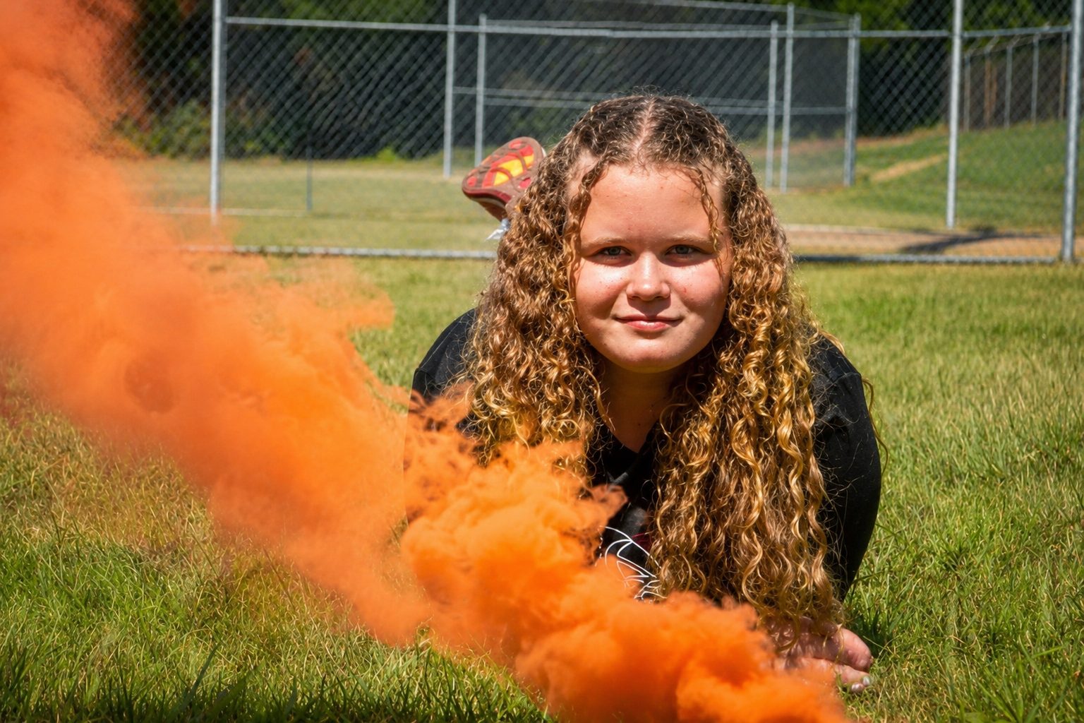 Senior portrait with an orange smoke bomb trailing across the frame