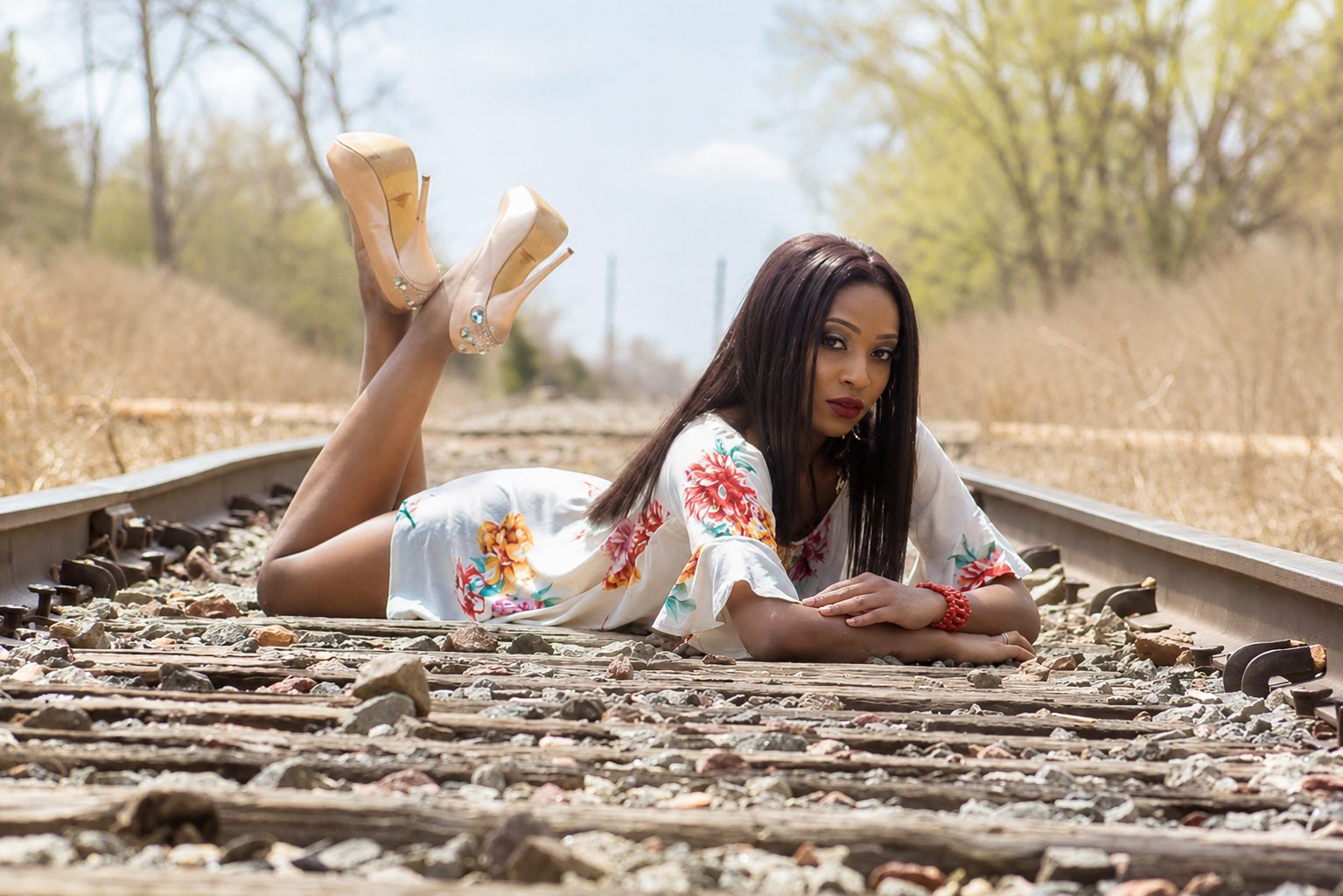 Editorial portrait lying along a set of railway tracks in spring